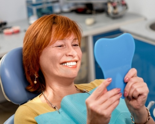 Woman looking at her smile after makeover