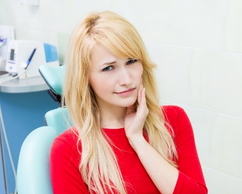 Woman in need of emergency dentistry holding cheek in pain