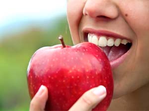 person biting into a red apple