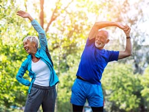 senior man and woman stretching while wearing exercise clothes