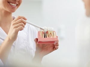 Dentist pointing to model explaining dental implants in New City, NY
