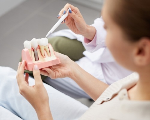 Dentist and patient looking at dental implant model