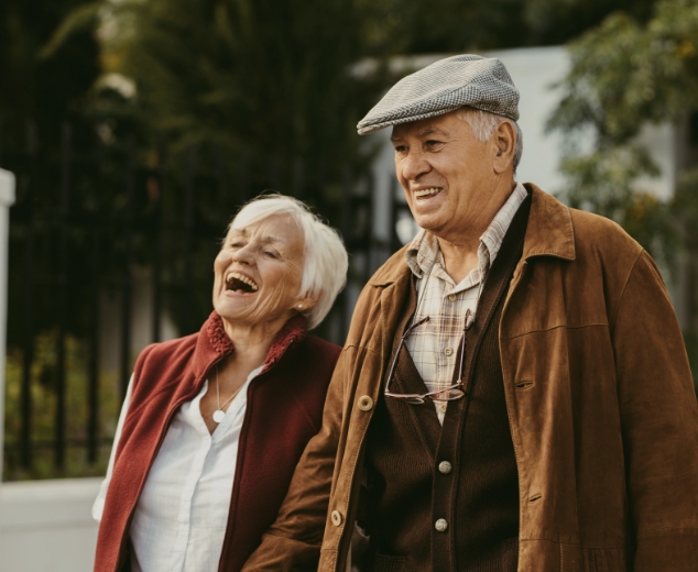 Older man and woman smiling after replacing missing teeth