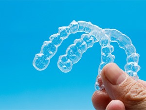 person holding two Invisalign aligners