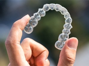 closeup of person holding Invisalign aligner  