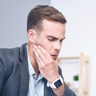 Man in need of emergency dentistry holding jaw in pain