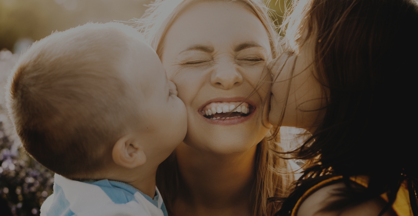 Children kissing mother on cheeks after receiving dental services